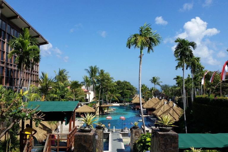 Tropischer Resort mit Swimmingpool, Palmen und blauem Himmel.